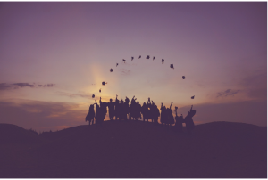 Graduates throwing caps at sunset